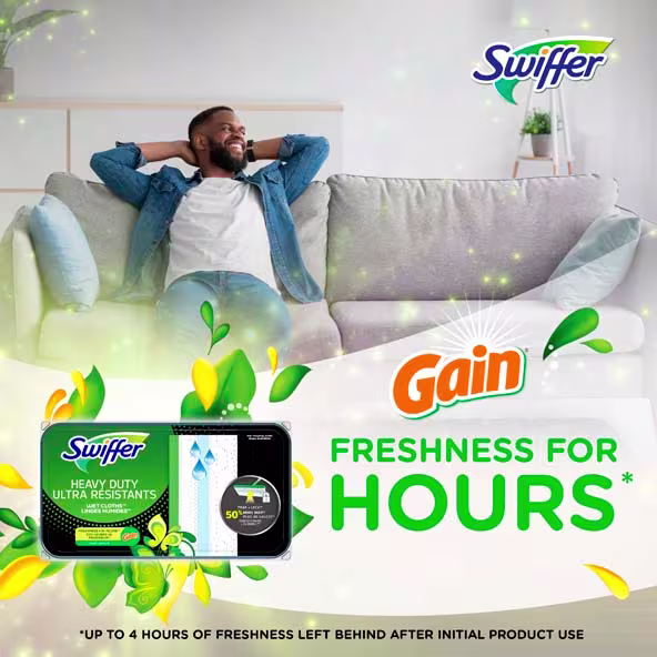 A relaxed man smiles while sitting on a couch, showcasing Swiffer Heavy Duty Wet Cloths with Gain scent