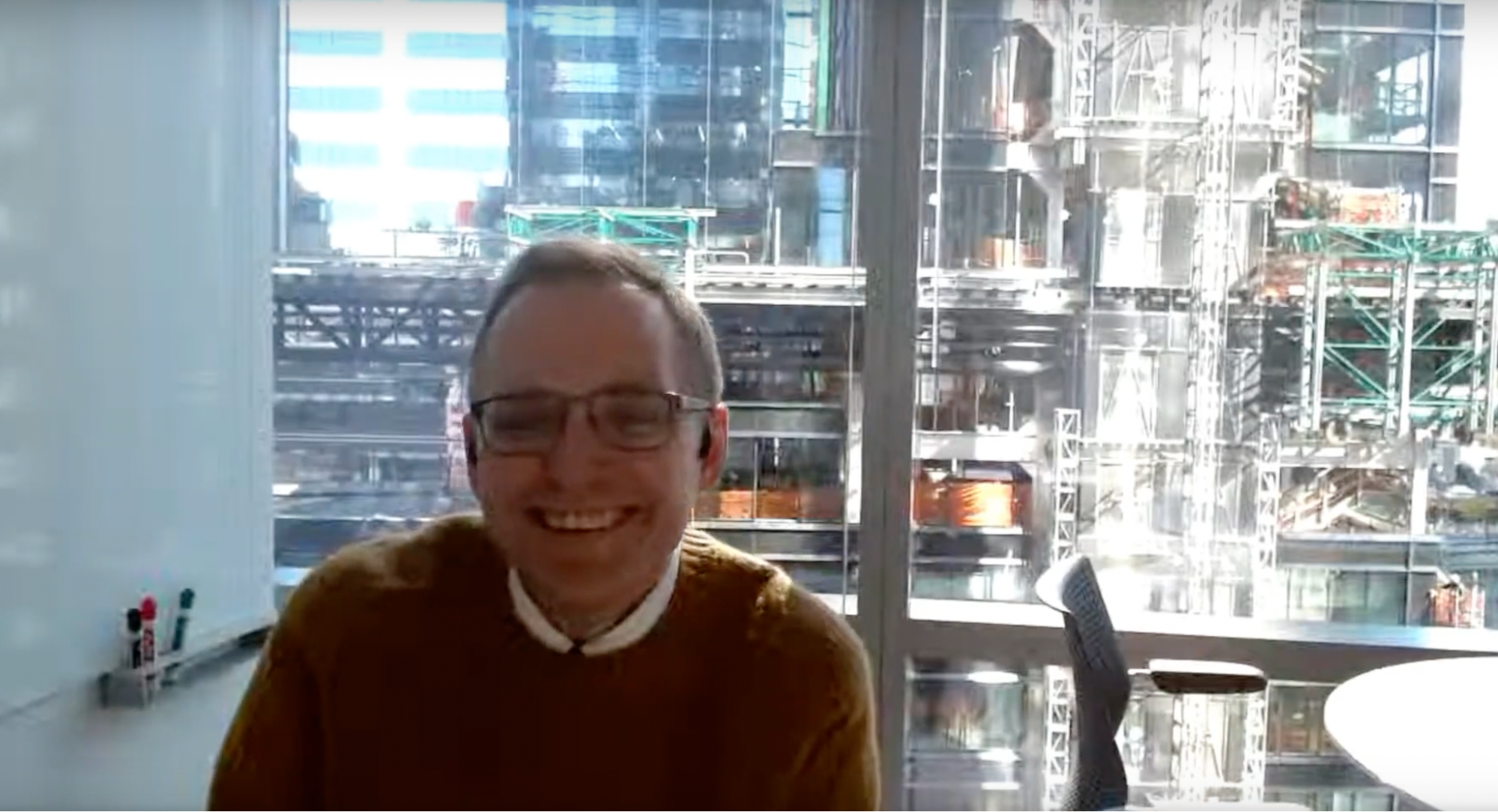 Ben Welsh smiling while on a video call in his office at Reuters in New York City, with a view of construction underway at One Times Square behind him.