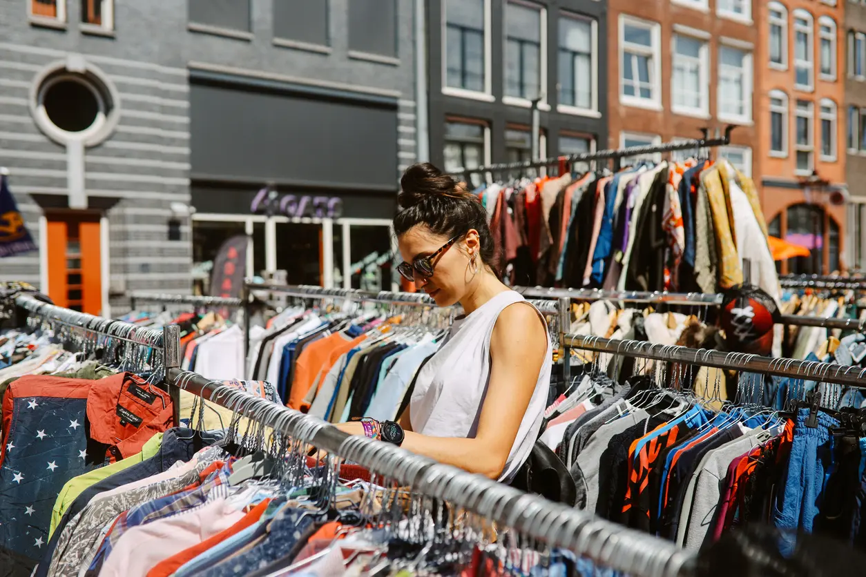 A woman looks through vintage clothing on a rack