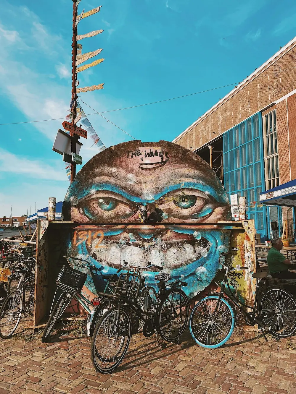 Bicycles in front of a wall mural of a face