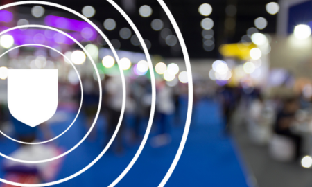 Blurred background of a busy exhibition with a sharp overlay of a white shield emblem