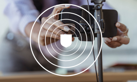 Person setting up a smartphone on a tripod, focusing on security with a shield icon overlay.