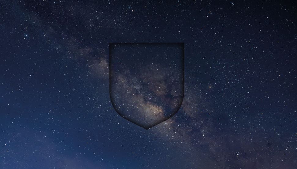 An image of the night sky, showing stars and galaxies. The dark outline of a shield has been superimposed over the top. 