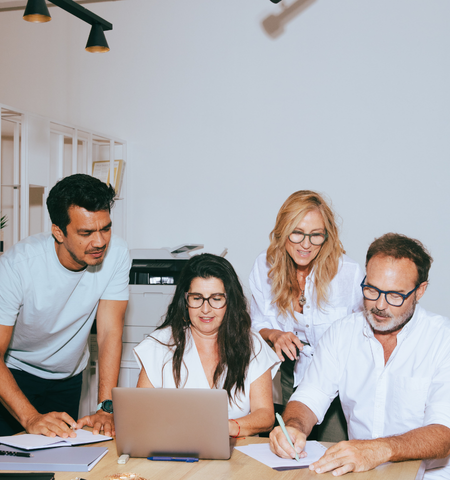 Four people sat and stood around a table in discussion