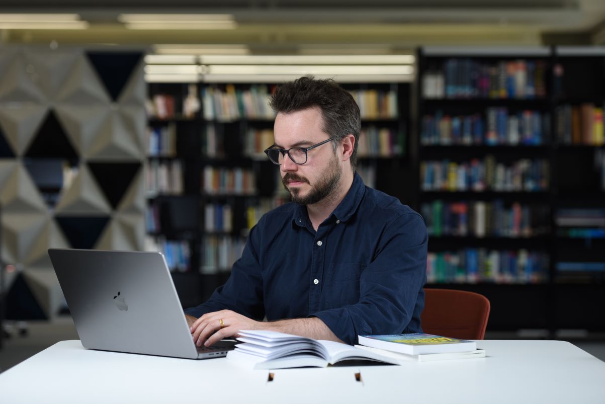 Man at table on laptop in library