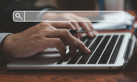 man typing at a laptop with search bar icon overlay