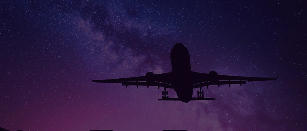 Silhouette of airplane flying at night