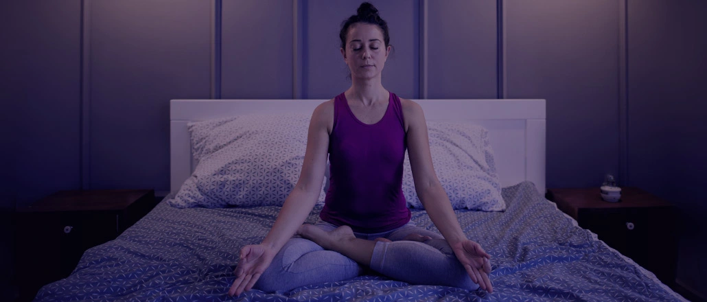 Young woman meditating in her bedroom