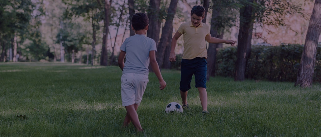 Two brothers playing soccer in the park