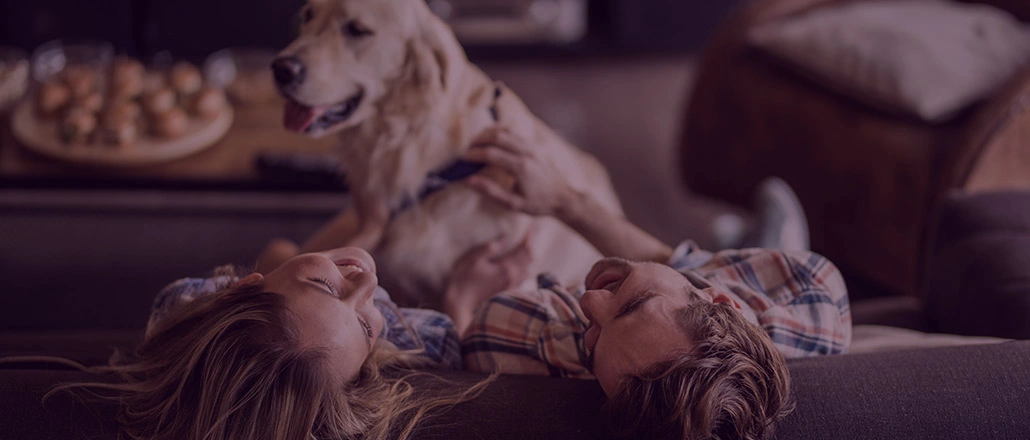 Happy couple laughing on couch with their dog