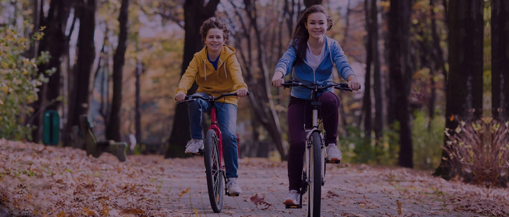 Brother and sister riding bikes in the park