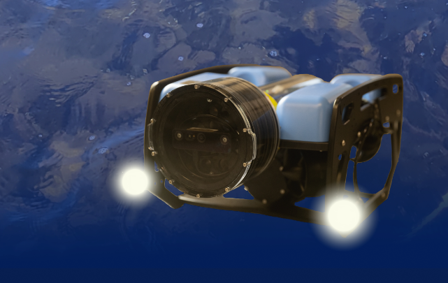 An underwater drone with a cylindrical camera and two bright lights hovers in a blue aquatic environment, suggesting exploration or surveillance. The drone has a robust frame and appears to be designed for deep-sea exploration.