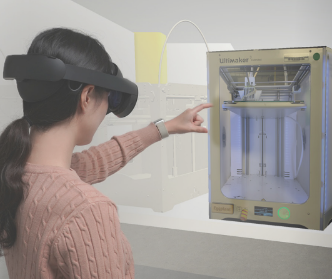 A person wearing augmented reality goggles interacts with a 3D printer. They point towards the printer, which is encased in a glass cabinet. The background is minimalist with a light color scheme.
