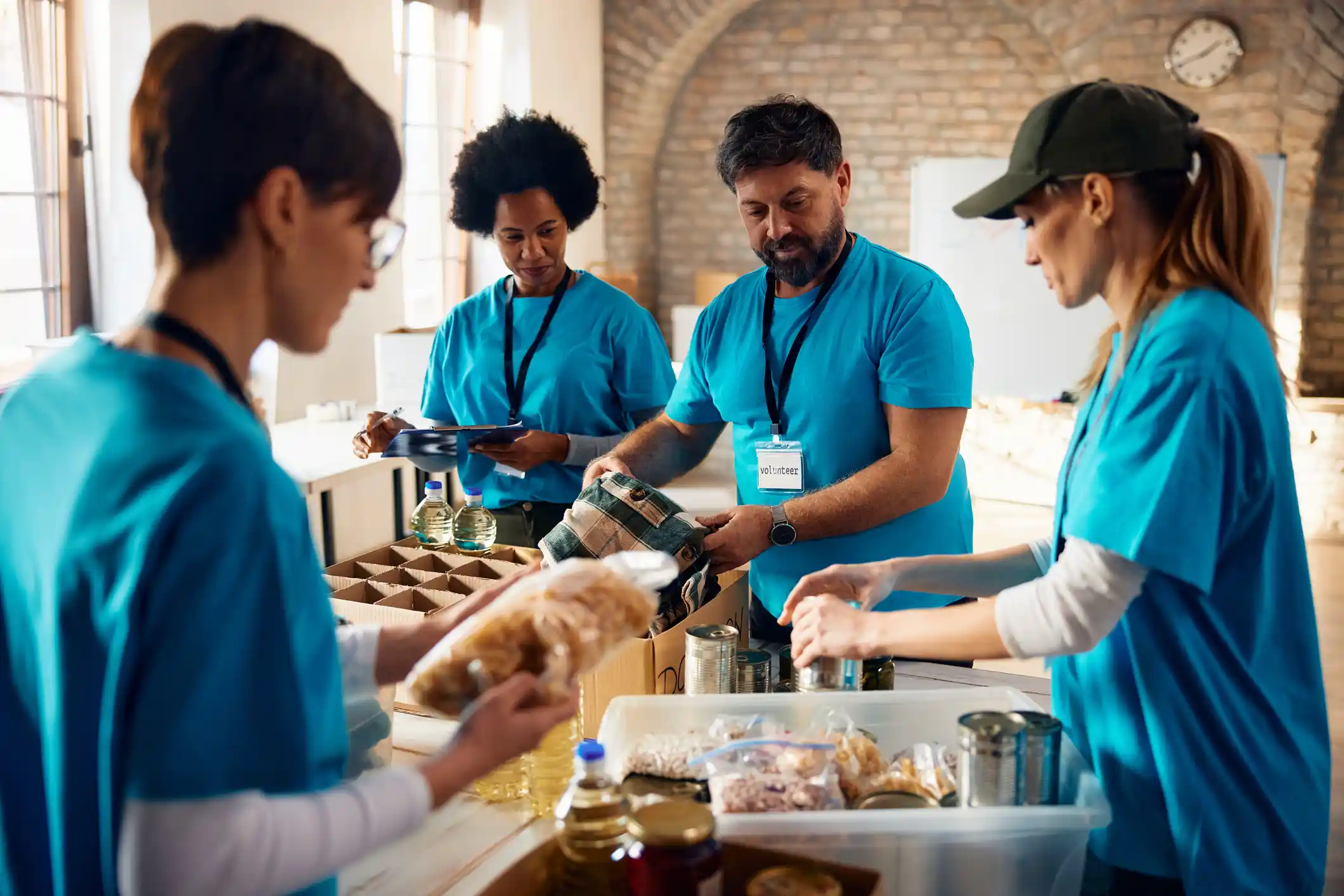 Four non-profit workers in blue t-shirts putting together care packages. 