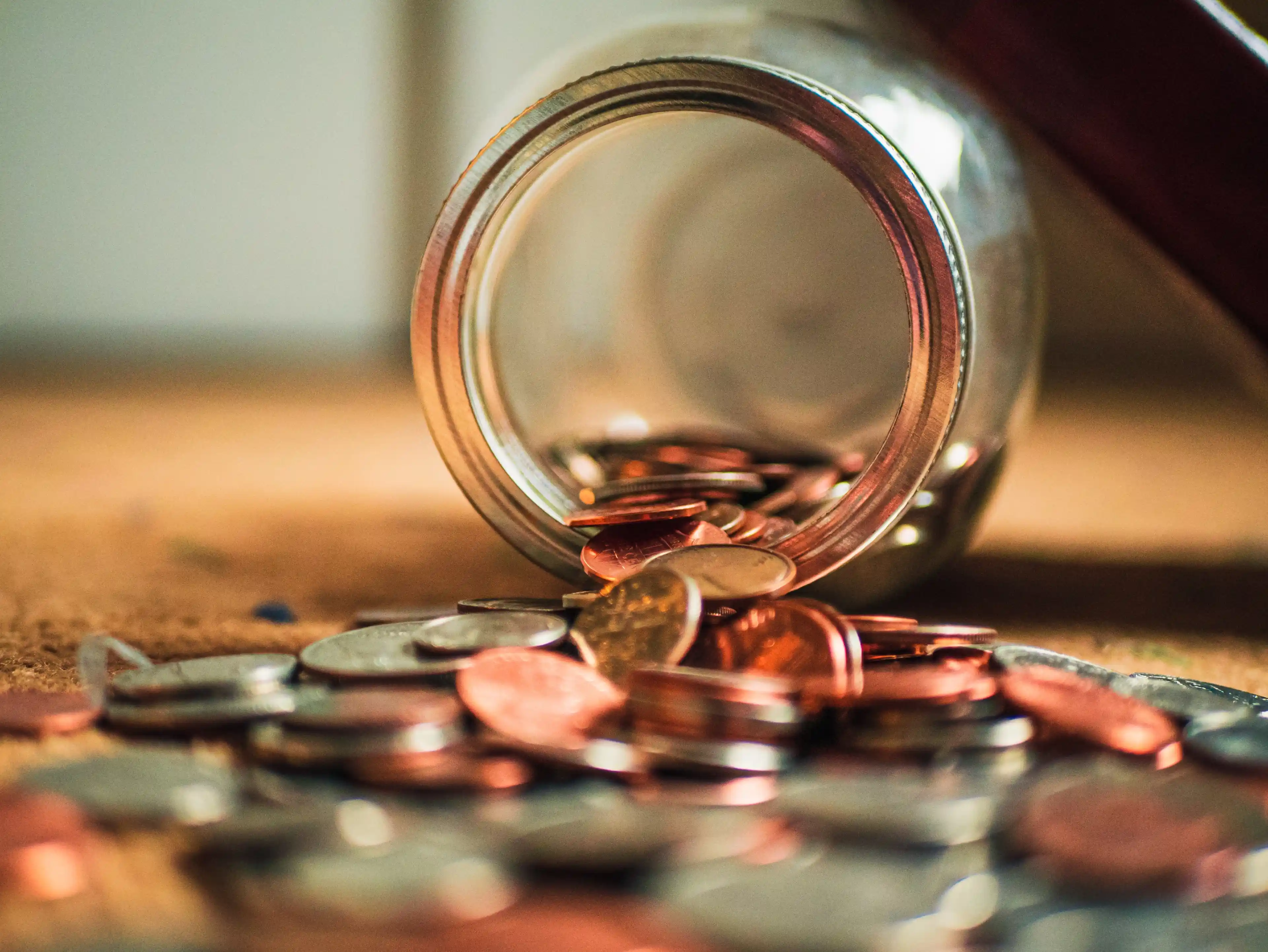 Coins spilled out of a knocked over glass jar