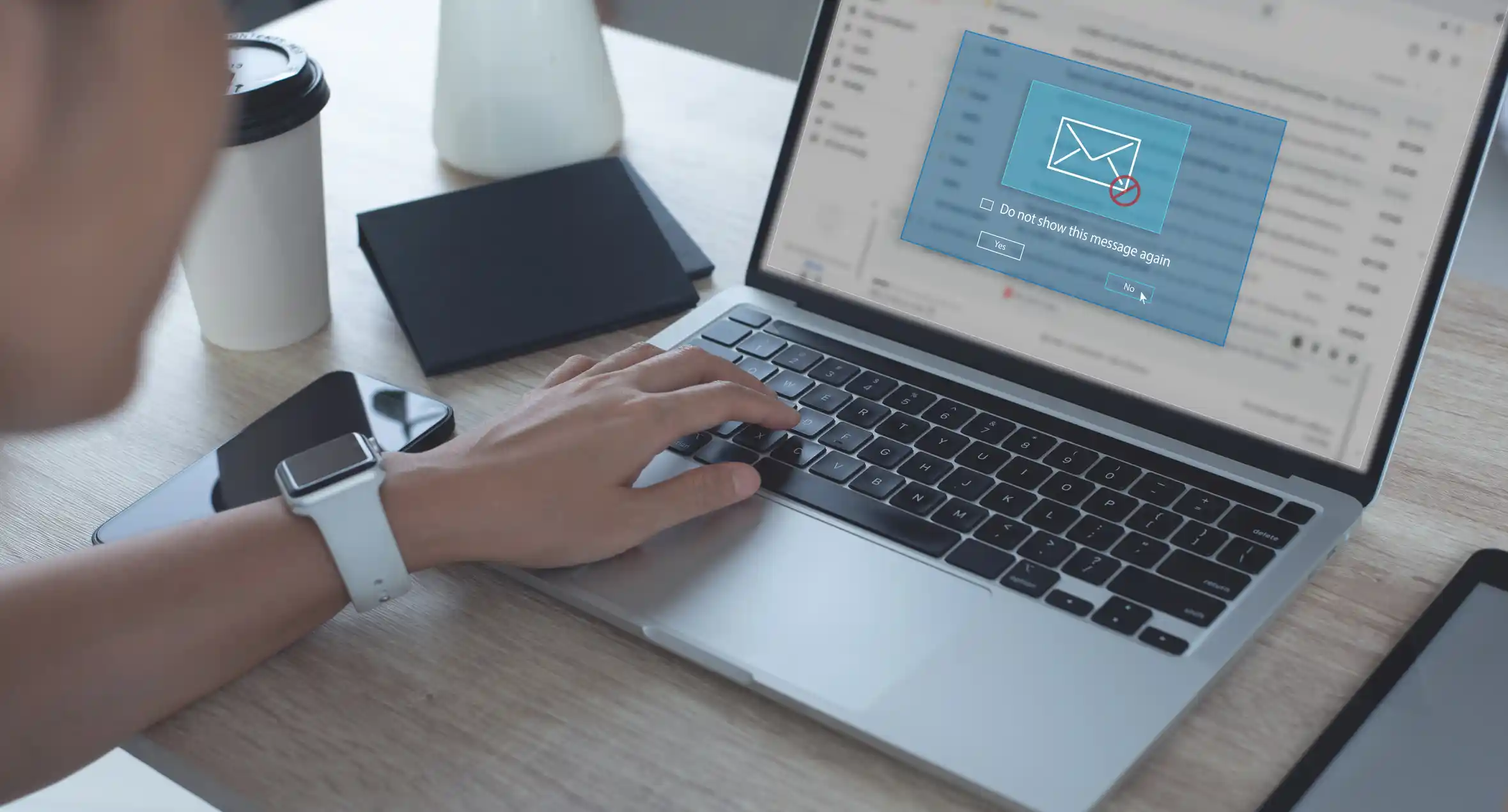 Person using a laptop with an email inbox open and a pop-up message displaying an envelope icon with a red “X.”