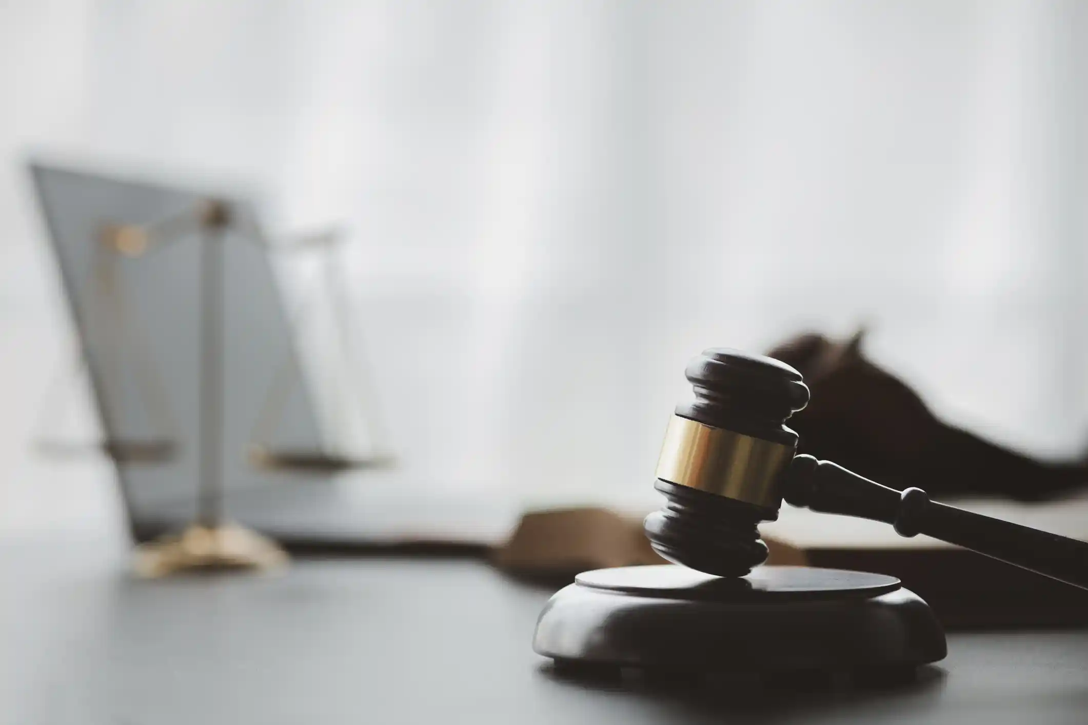 Judge’s gavel with scales of justice and a laptop in the background.