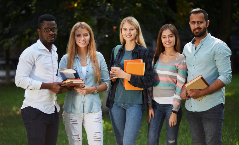 A group of IELTS test takers holding books and walking in a park