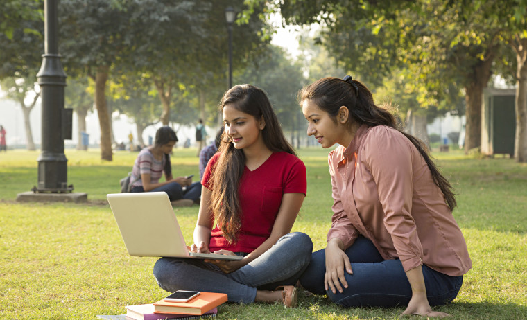 Two female IELTS test takers prepare for IELTS test in their laptop at a park