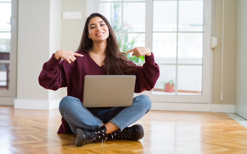 Female IELTS test taker in red full-sleeve t-shirt points her finger at her laptop