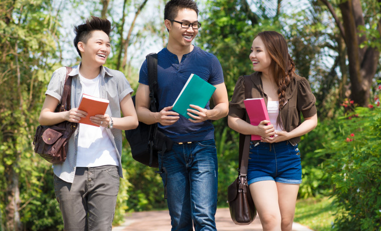 Three IELTS test takers walking down a university pathway and happily talking