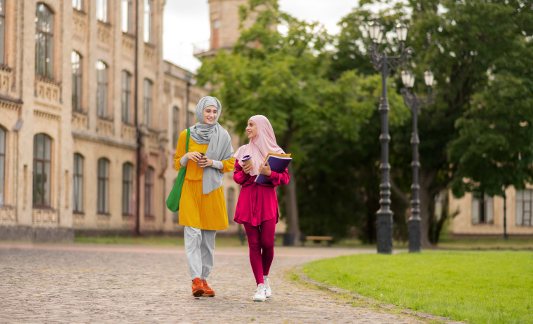 Two female test takers wearing hijabs walking in a university