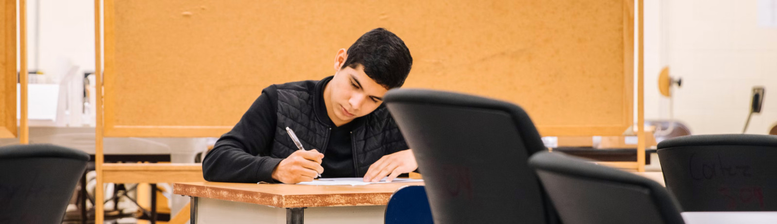 A male test taker preparing for IELTS Writing test in a classroom