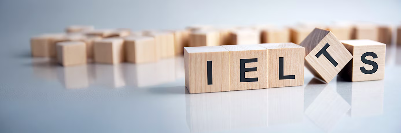 Banner image for the article IELTS for Beginners: A Simple Step-by-Step Guide-The word IELTS on wooden cubes, grey background