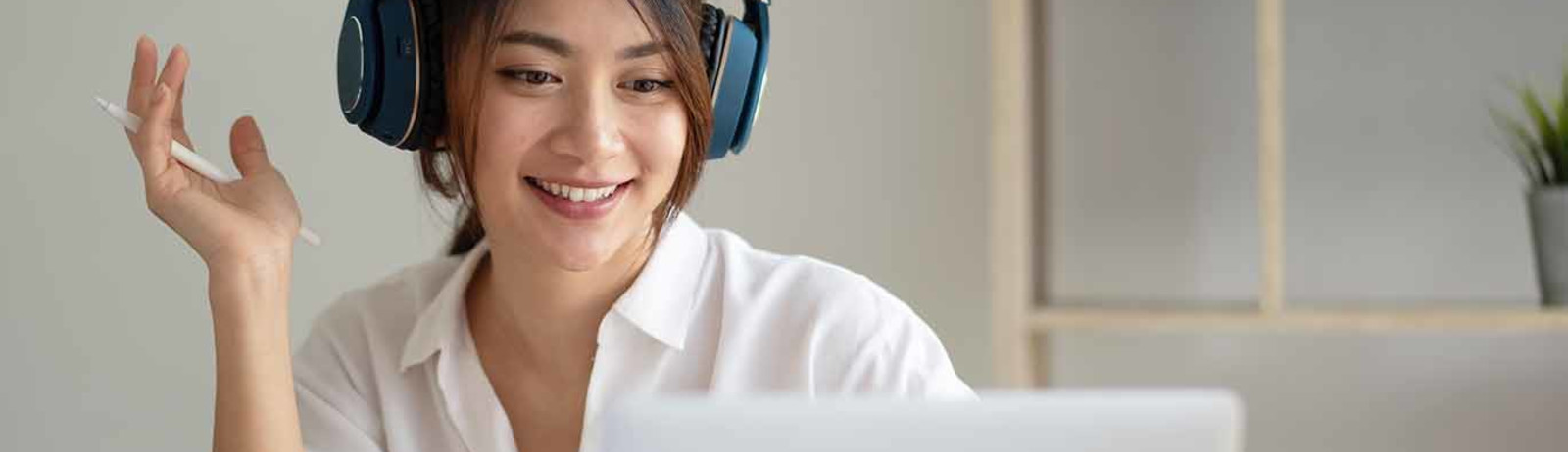 A female IELTS test taker wearing headphones preparing for IELTS test on her laptop