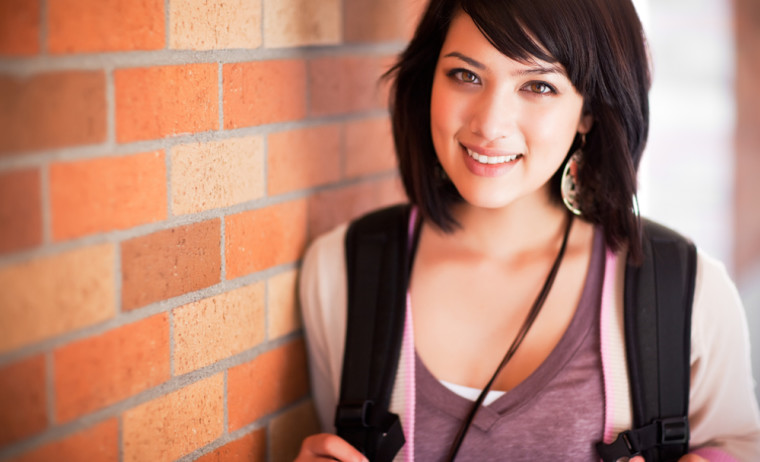 Smiling woman leaning against a brick wall