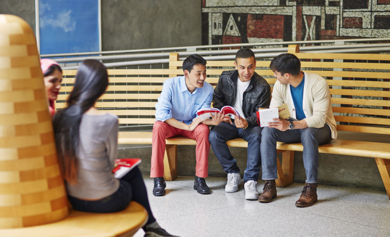 Three test takers sit and talk through the official IELTS preparation materials