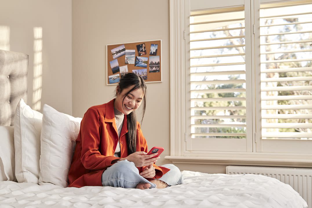 Functional Language: Expressions for Speaking blog post image - Girl smiling at red phone on bed near window