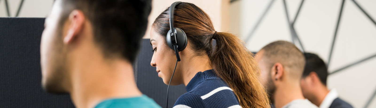 Female test taker in navy blue t-shirt listens to an audio in the Listening test during an IELTS on computer session