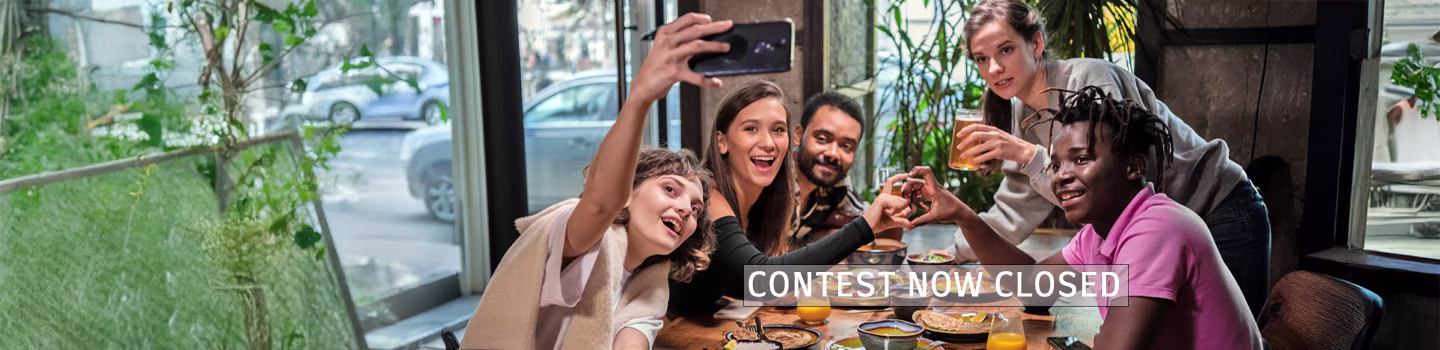 A group of smiling friends take a picture at a restaurant table