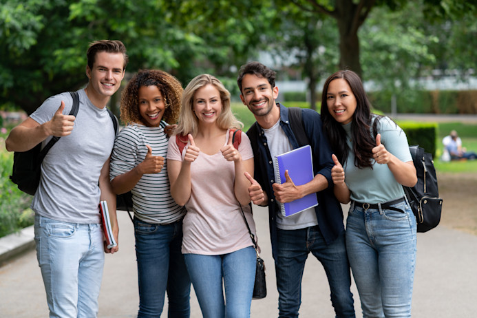Two male and three female IELTS test takers giving a thumbs up sign