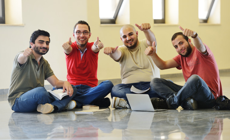 Group of IELTS test takers sitting on the floor and posing a thumbs up sign 