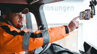 Mann in Warnjacke tipps auf Handy an der Windschutzscheibe intelligente Lösungen Vialytics