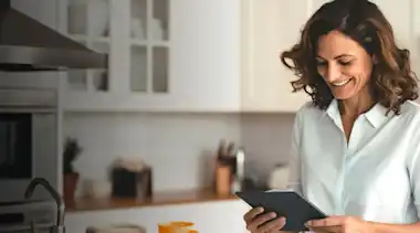 Lächelnde Frau mit Tablet in der Küche