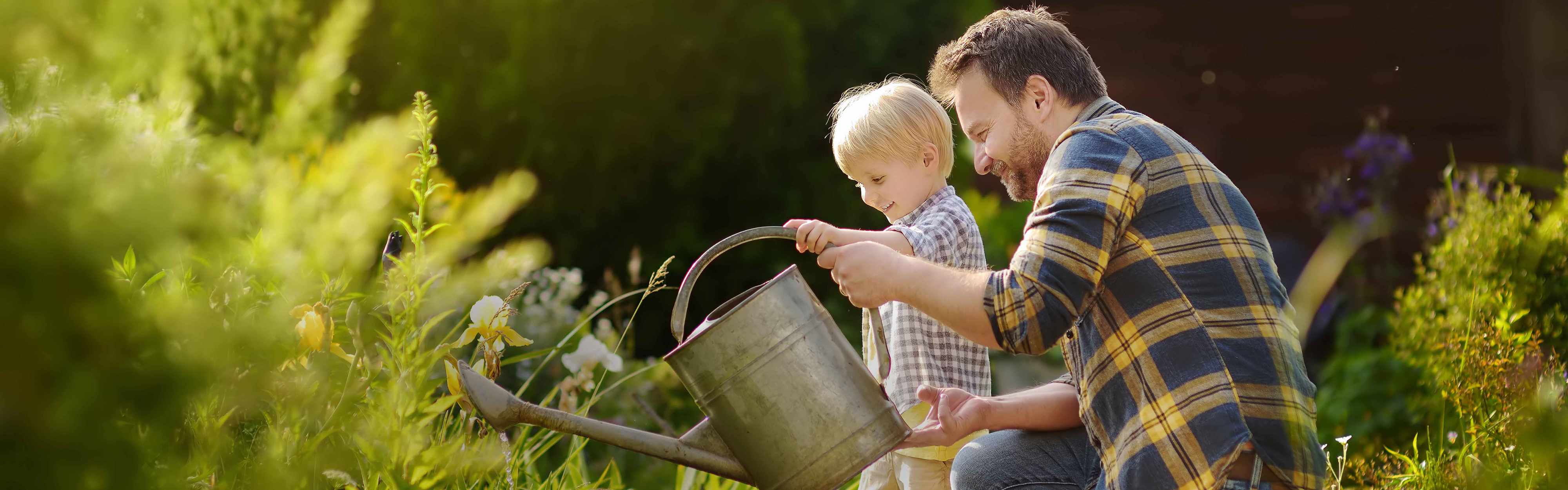 Vater und Sohn gießen Garten mit Gießkanne