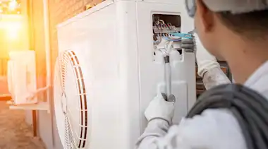 Experte baut eine Wärmepumpe vor einem Haus ein