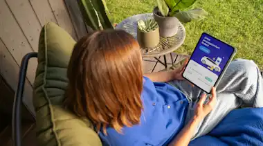 Eine Frau steuert EnBW Mavi, die Energie-Managerin zuhause im Garten über die EnBW zuhause+ App am Tablet.