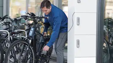 Mann lädt sein Fahrrad an der Velobox von Zigmo