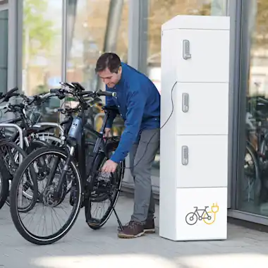 Mann lädt sein Fahrrad an der Velobox von Zigmo