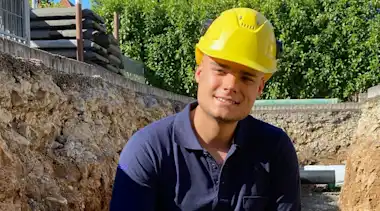 Mann mit Helm in Baugrube