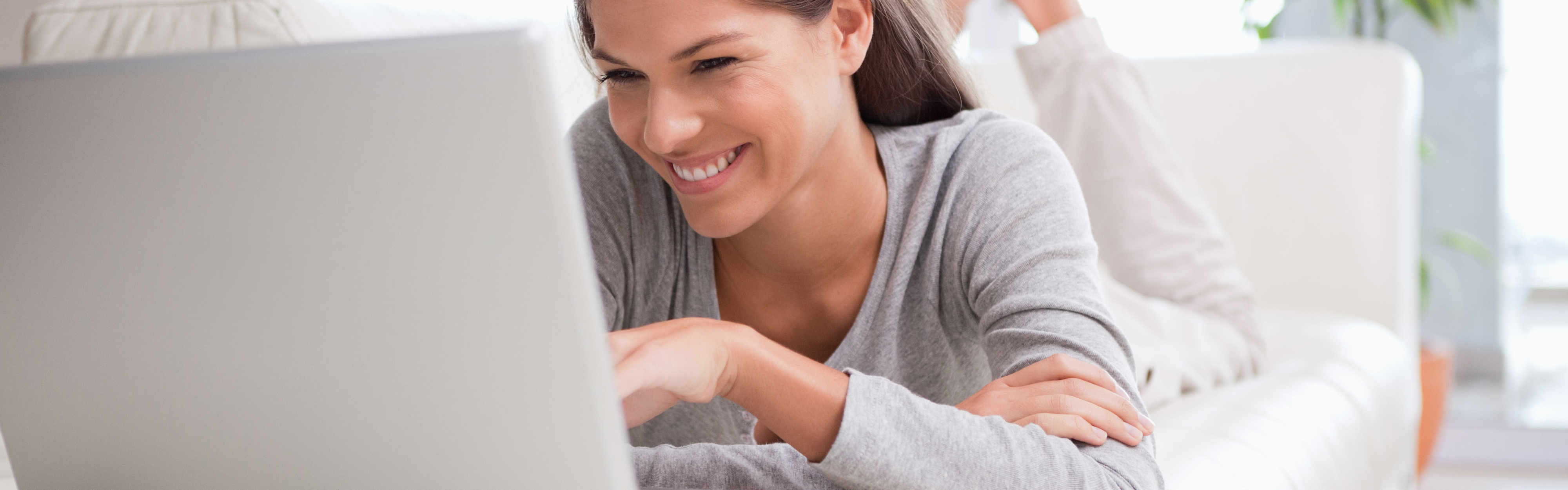 Frau arbeitet auf der Couch mit einem Notebook