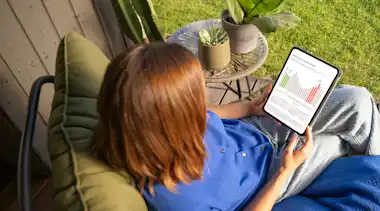 Eine Frau ist am Tablet auf der EnBW Dynamischer Stromtarif-Seite im Garten