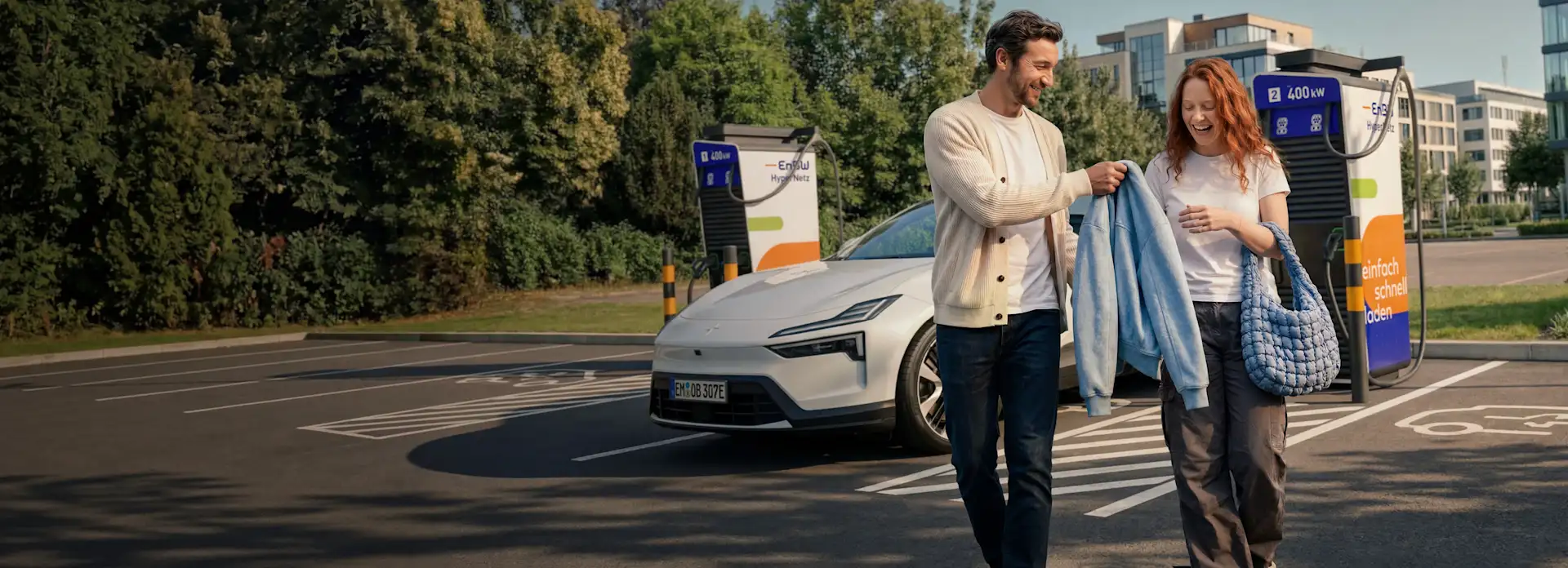 KI-generiert: Pärchen an Ladestation lächelt und geht vom Auto weg.