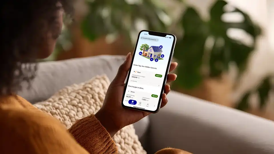 Frau hält Smartphone in der Hand mit der Startseite der EnBW zuhause+ App