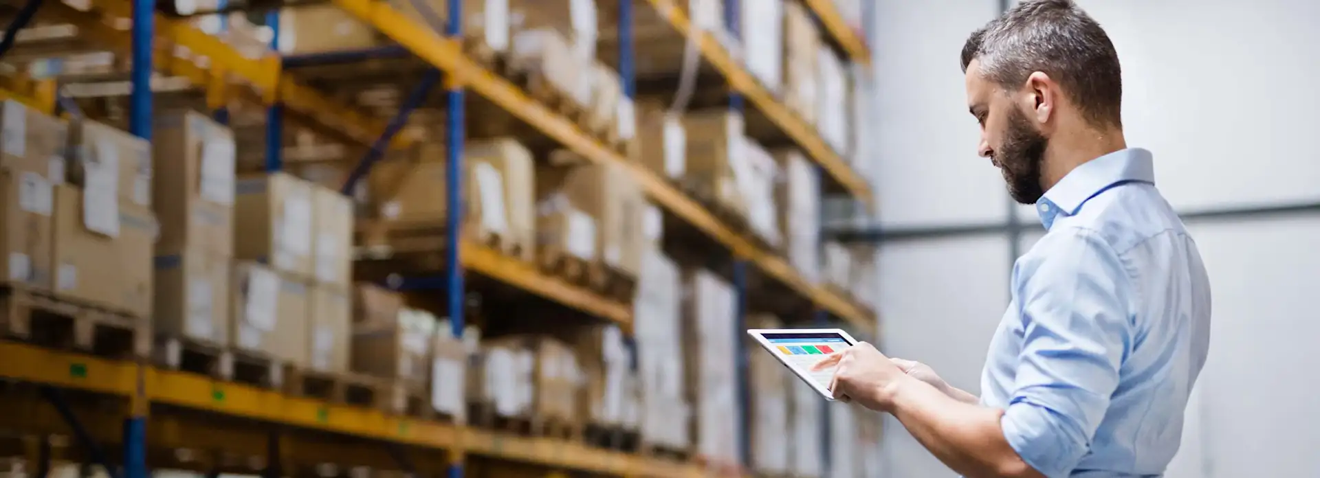 Mann mit Tablet vor einem Hochregal Einkauf Logistik
