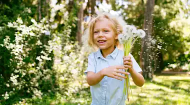 Mädchen rennt mit Pusteblumen im Wald